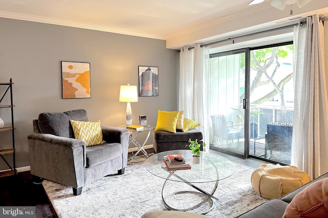 living area featuring baseboards, ornamental molding, a ceiling fan, and wood finished floors