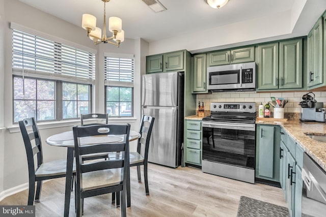 kitchen featuring visible vents, green cabinetry, appliances with stainless steel finishes, and a notable chandelier