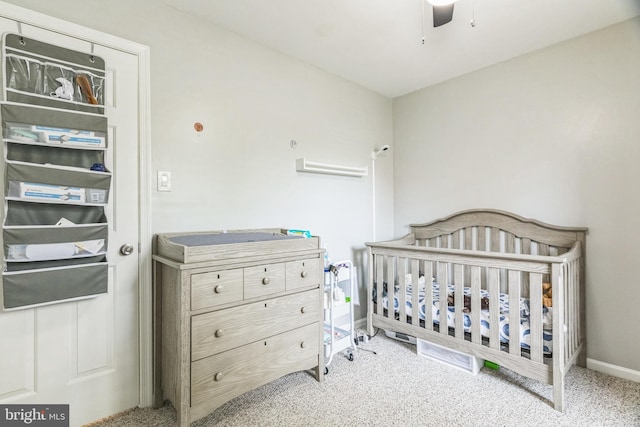 bedroom featuring carpet floors, baseboards, ceiling fan, and a crib