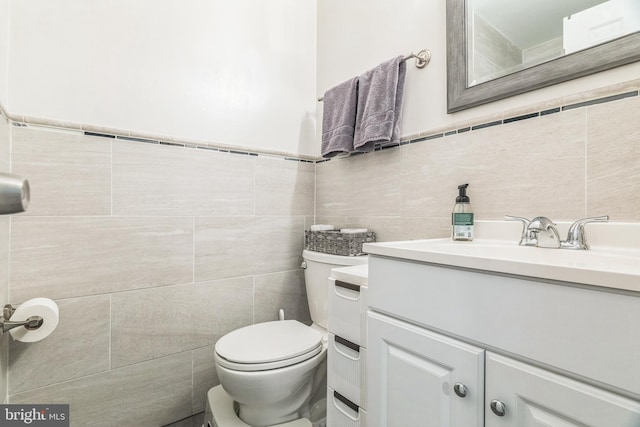 half bath with toilet, tile walls, and vanity