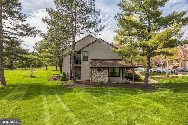 rear view of house with a lawn and stone siding