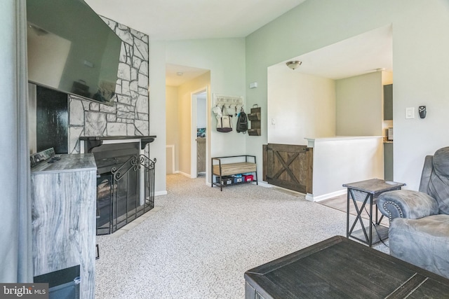 living area featuring baseboards, vaulted ceiling, carpet, and a fireplace