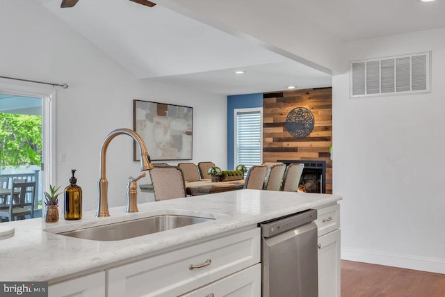 kitchen featuring a sink, dishwasher, light stone countertops, and visible vents