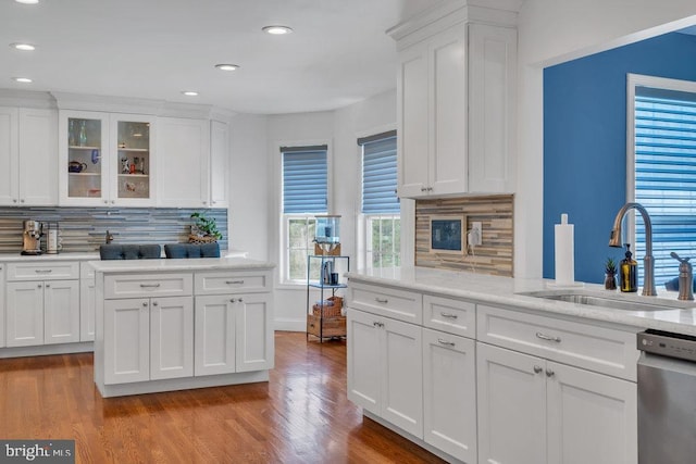 kitchen featuring backsplash, dishwasher, a sink, white cabinets, and light wood-style flooring