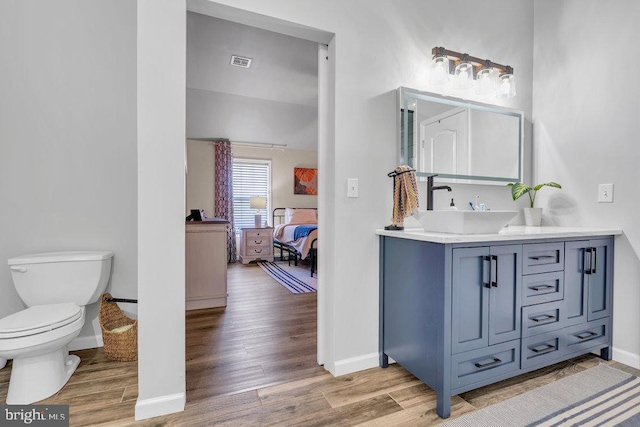 bathroom with toilet, baseboards, visible vents, and wood finished floors