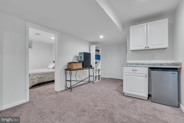 kitchen featuring white cabinets, fridge, baseboards, and light colored carpet