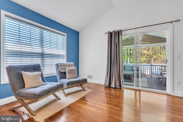 living area featuring baseboards, visible vents, wood finished floors, and lofted ceiling