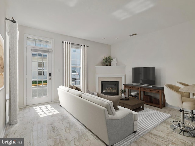 living room featuring visible vents, a glass covered fireplace, and marble finish floor