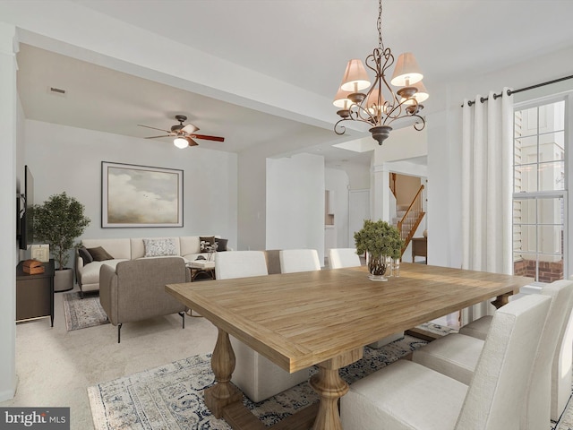 dining room featuring visible vents, stairs, and ceiling fan with notable chandelier