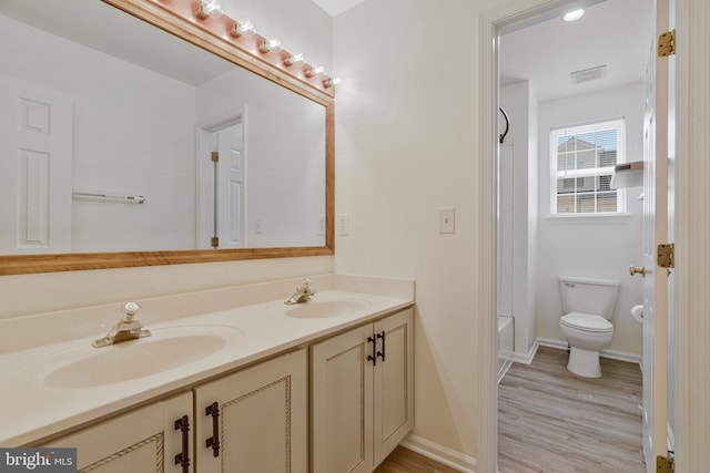 bathroom with double vanity, a sink, wood finished floors, and toilet