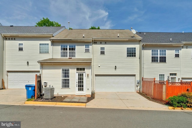 rear view of property with a garage, central AC, and driveway