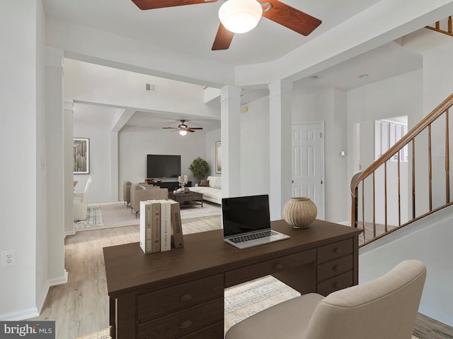 office featuring decorative columns, a ceiling fan, light wood finished floors, and visible vents