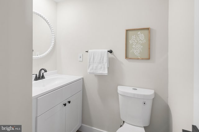 half bath featuring vanity, baseboards, and toilet