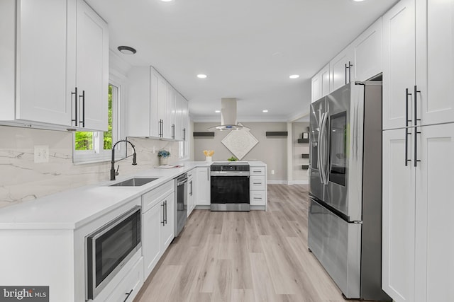 kitchen featuring island exhaust hood, a sink, light countertops, white cabinets, and stainless steel appliances