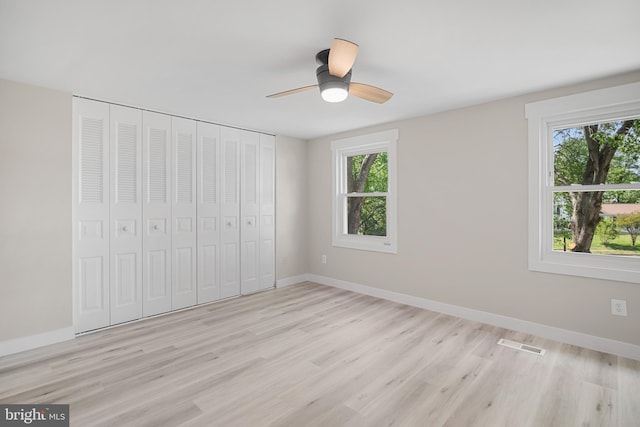unfurnished bedroom featuring light wood-style floors, baseboards, and multiple windows