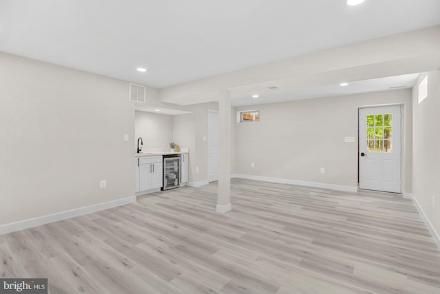 basement with wine cooler, recessed lighting, wet bar, and a sink