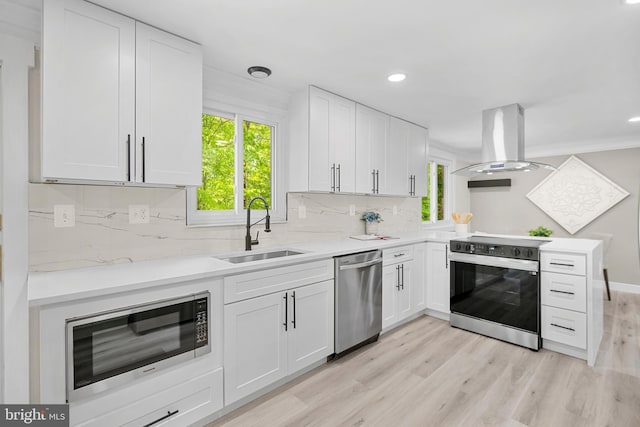 kitchen featuring decorative backsplash, island range hood, a sink, light countertops, and stainless steel appliances