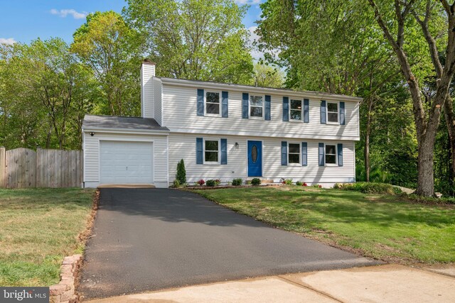 colonial inspired home with driveway, a chimney, a front yard, a garage, and fence