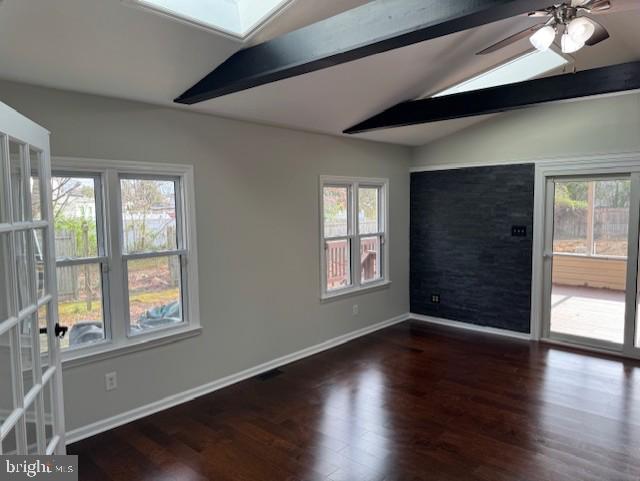 unfurnished room with baseboards, ceiling fan, wood finished floors, and vaulted ceiling with skylight