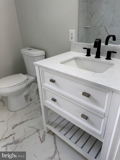 bathroom featuring toilet, marble finish floor, and vanity