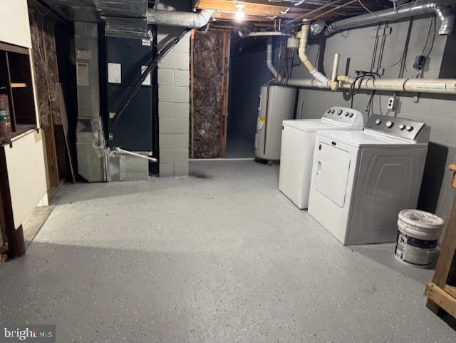 unfinished below grade area featuring concrete block wall, heating unit, washing machine and dryer, and water heater