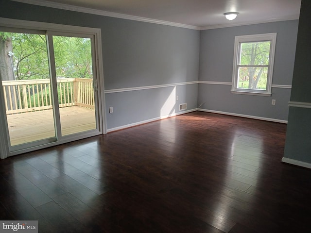 empty room featuring baseboards, ornamental molding, dark wood-style flooring, and visible vents