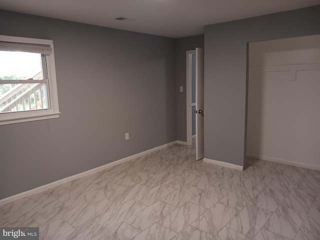 unfurnished bedroom featuring baseboards, a closet, and marble finish floor