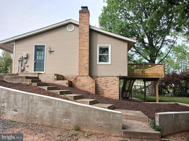 back of house featuring a chimney, a wooden deck, and stairway