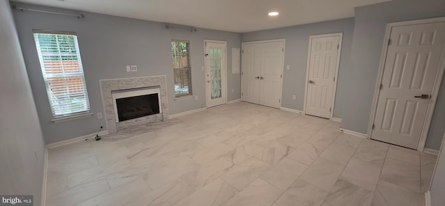 43183 Glenelder Ter, Ashburn, VA 20147 - unfurnished living room featuring light marble finish flooring, a high end fireplace, and recessed lighting