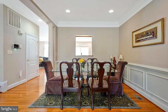 dining room with crown molding, decorative columns, wood finished floors, and visible vents