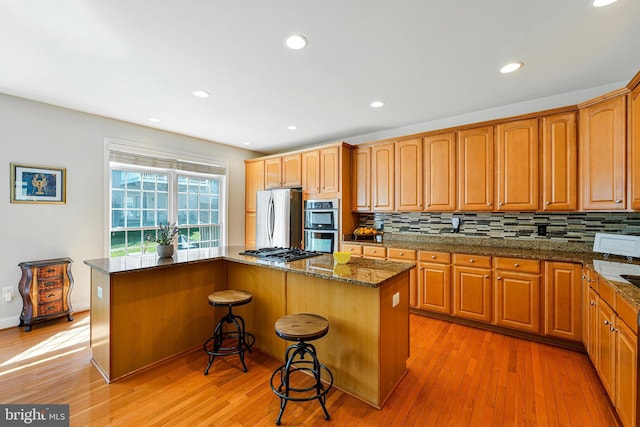 kitchen featuring a center island, tasteful backsplash, stainless steel appliances, and light wood-type flooring