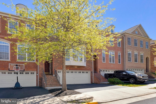 view of property with an attached garage, driveway, and brick siding