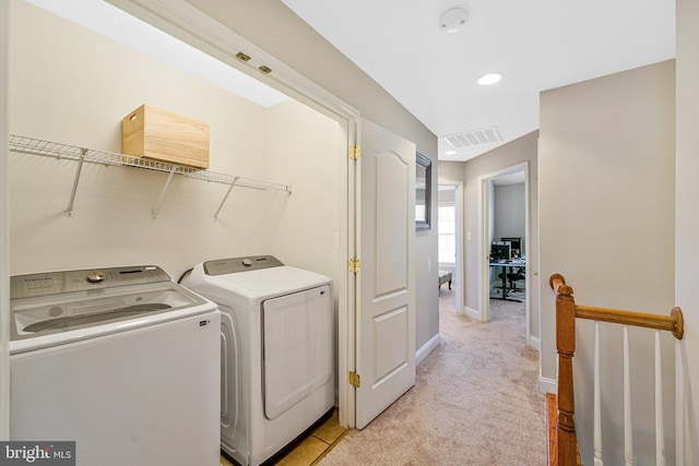 clothes washing area featuring laundry area, light carpet, baseboards, visible vents, and washer and clothes dryer
