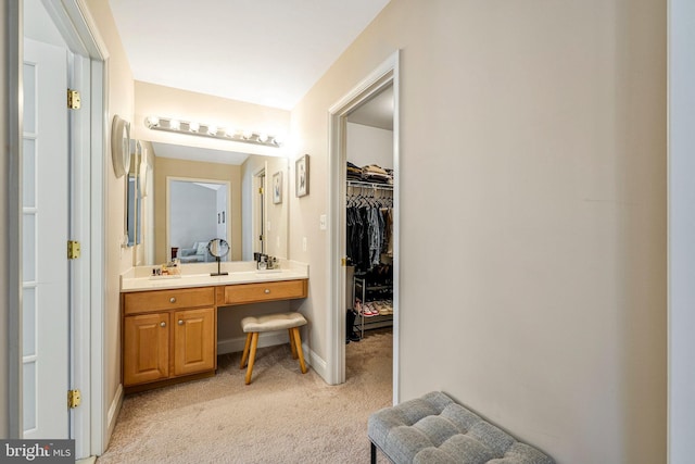 bathroom with vanity, baseboards, and a spacious closet