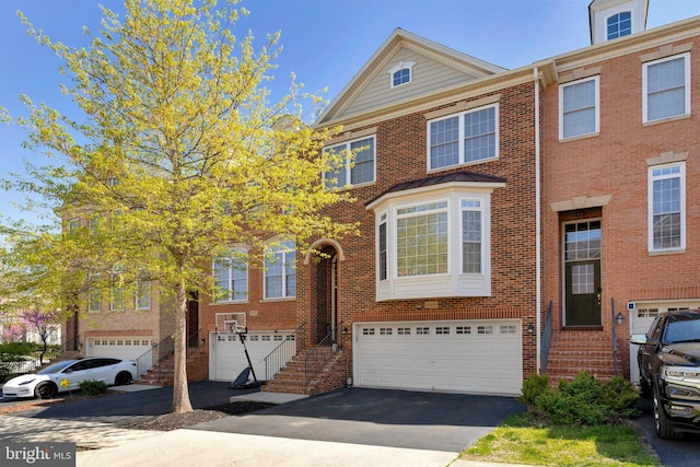multi unit property with a garage, driveway, and brick siding