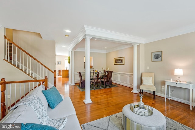 living area with crown molding, wood finished floors, stairway, ornate columns, and recessed lighting