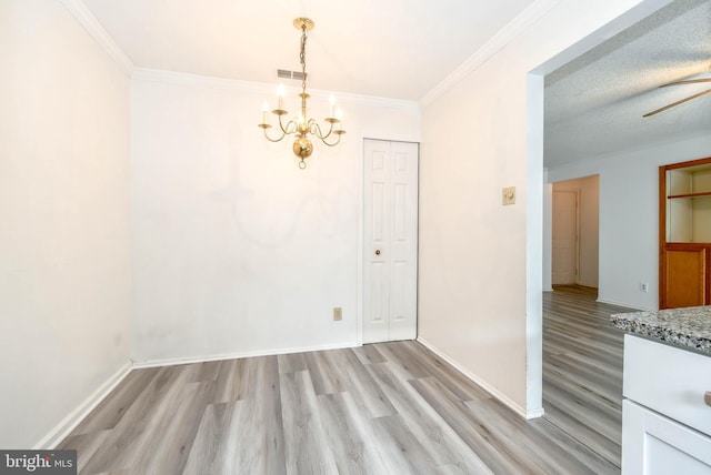 unfurnished dining area featuring baseboards, visible vents, light wood finished floors, and a notable chandelier