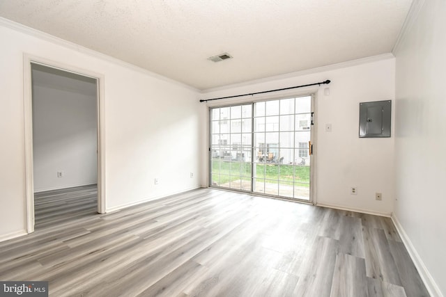 empty room featuring electric panel, a textured ceiling, visible vents, crown molding, and light wood-style flooring