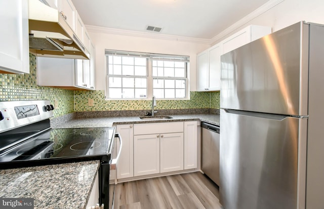 kitchen featuring a sink, under cabinet range hood, ornamental molding, stainless steel appliances, and white cabinetry