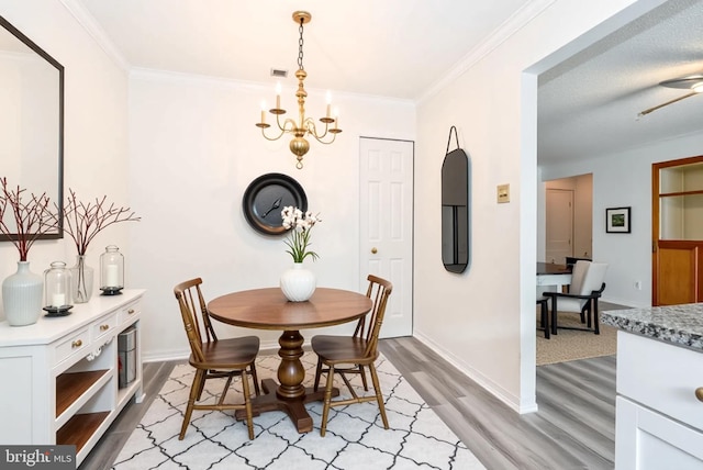 dining area with visible vents, baseboards, a notable chandelier, light wood-style floors, and ornamental molding