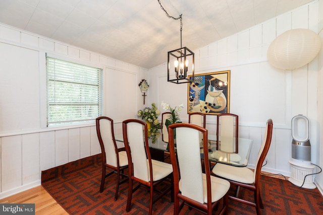 dining room with an inviting chandelier, wood finished floors, and a decorative wall