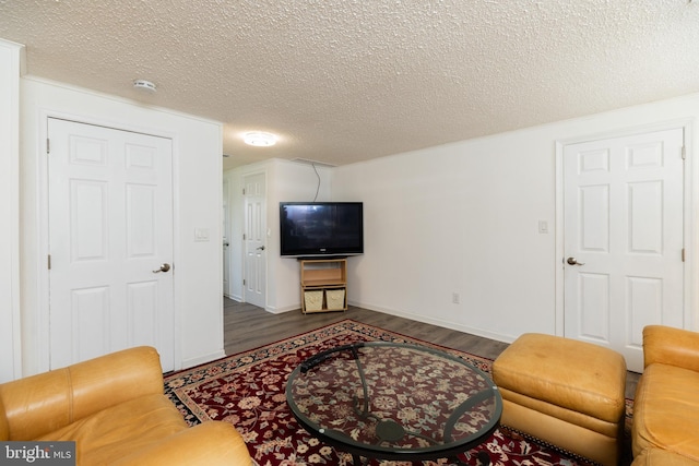 living room with dark wood-style flooring, a textured ceiling, and baseboards