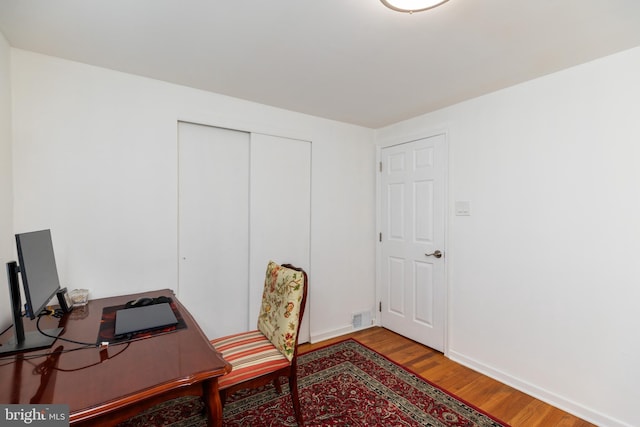 office space with baseboards, wood finished floors, and visible vents