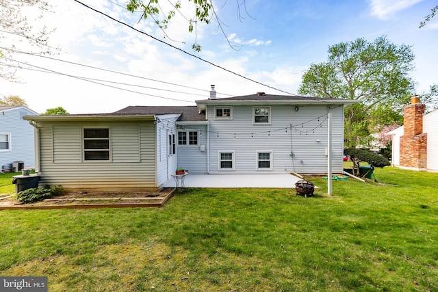back of property with a lawn, a patio, a fire pit, and central AC unit
