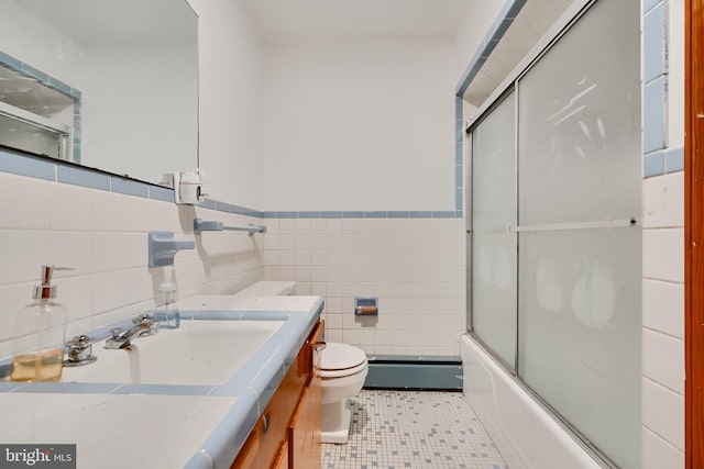 full bath featuring tile patterned flooring, vanity, toilet, tile walls, and a wainscoted wall