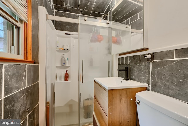 full bath with vanity, a stall shower, toilet, and tile walls