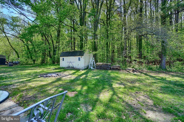 view of yard with an outbuilding, a shed, and a wooded view