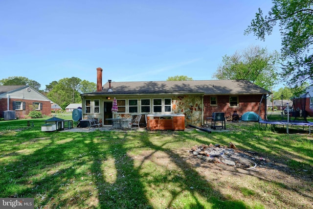 back of house featuring a chimney, a trampoline, a patio area, central air condition unit, and a jacuzzi
