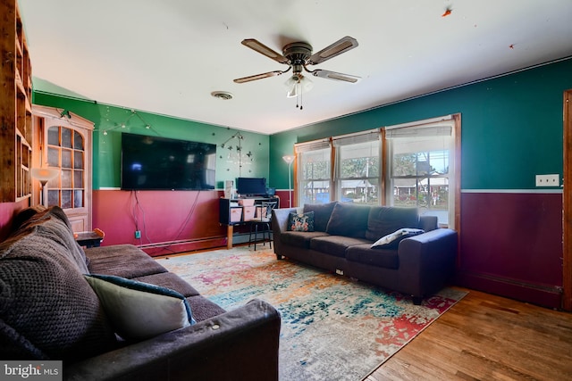 living area with visible vents, a ceiling fan, and wood finished floors