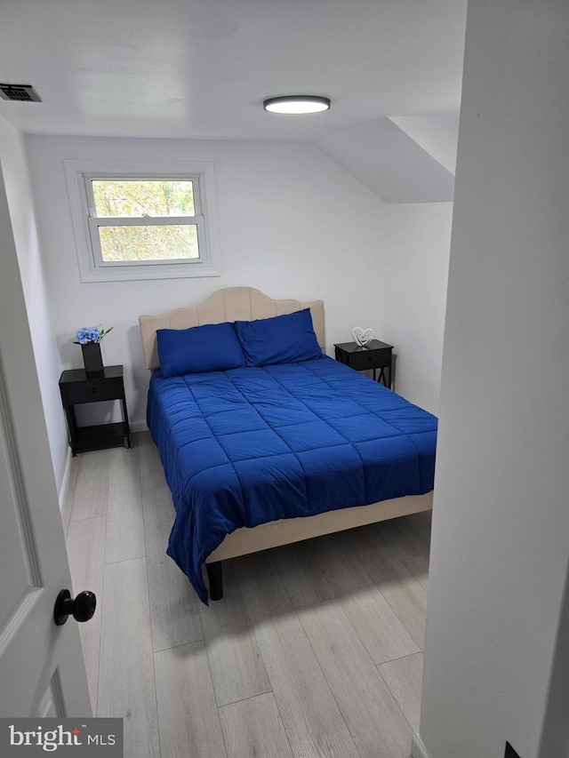 bedroom featuring lofted ceiling, wood finished floors, and visible vents